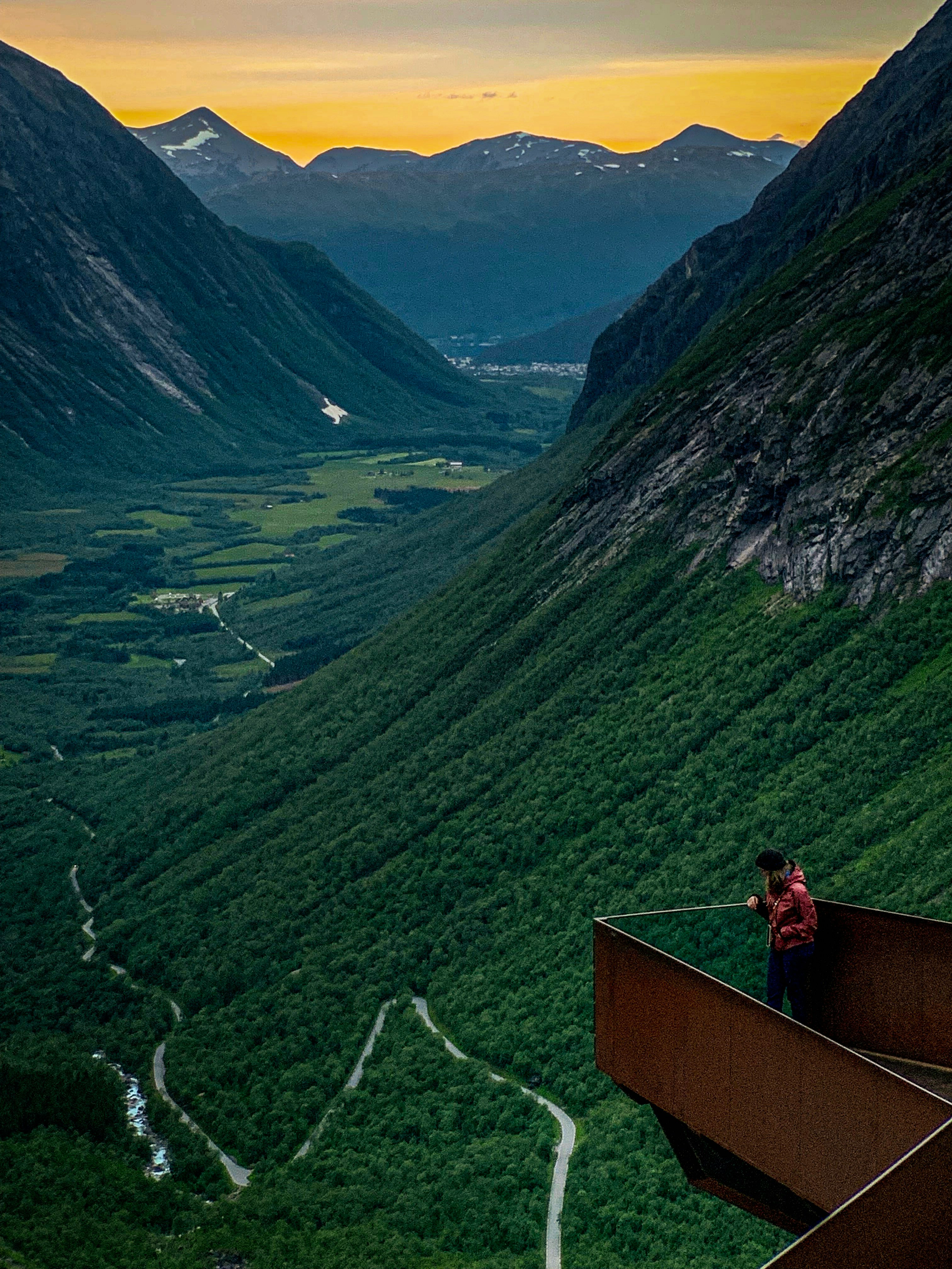 man standing on metal balcony near the mountains